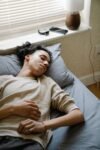 Person sleeping beside a smartphone and smartwatch used for sleep tracking