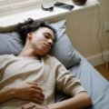 Person sleeping beside a smartphone and smartwatch used for sleep tracking