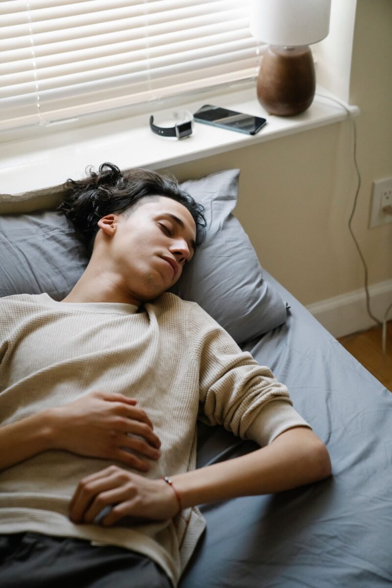 Person sleeping beside a smartphone and smartwatch used for sleep tracking